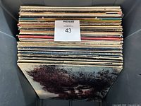 Photo showing the full lot of approximately 42 LP records stacked vertically in a grey bin, with visible worn album edges