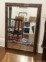 Full view of the large rectangular mirror standing against the wall, showing the reflective surface and the faux birdseye wood frame pattern.