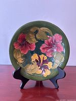 Front view showing colorful Hibiscus floral pattern on green background with a display stand.