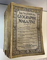Stack of vintage National Geographic magazines, topmost issue December 1920, showing aged paper covers with text and decorative borders.