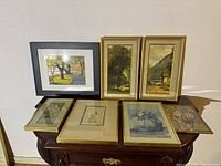 All six framed prints and one signed etching arranged on a table, showing various landscapes, birds, and scenes.