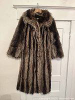 Front view of the long raccoon fur coat showing striped natural fur pattern and long sleeves.