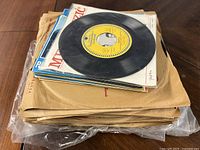 Stack of vintage vinyl records with visible black records and various branded paper sleeves.
