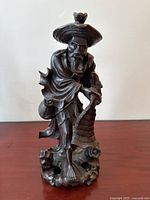 Front view of antique rosewood carved Immortal Fisher figure showing detailed face, hat, robes, fishing net, and basket on natural base.