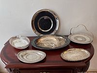 Overview of all 6 silverplate trays on wooden table
