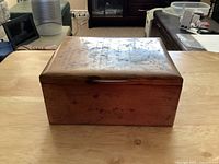 Closed rectangular copper box with a hinged lid, showing patina and slight marks on copper surface