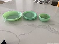Five jadeite pieces displayed on countertop: three plates stacked, one shallow bowl and one small bowl