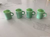 Four jadeite mugs side by side on countertop