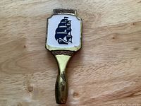 Top down view of Molson Export brass beer tap handle showing blue sailing ship design and embossed Molson and Export branding.