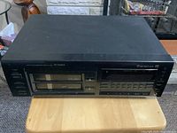 Front view showing the two disc trays, control buttons, and branding on the unit.