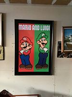 Framed Super Mario and Luigi poster hung on a beige wall, showing the entire artwork and frame clearly.