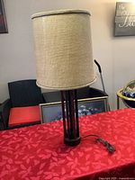 Full view of teak table lamp with fabric shade on a red tablecloth.