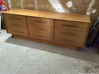 Front view of teak nine-drawer dresser on plinth base