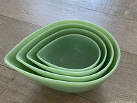 Four jadeite bowls nested together on wooden floor