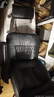 Black leather recliner pedicure chair angled showing seat, backrest, and armrests.