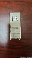 Front view of the Helena Rubinstein Prodigy Cellglow skincare sealed box on wooden surface showing brand and product details.
