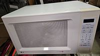 Front view of the white LG microwave oven with a door featuring a mesh-covered window and control panel on the right.
