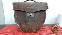 Original brown leather carrying case, showing worn leather flap and metal lock clasp.
