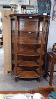 Antique oak display cabinet with wood curved side panels replacing original glass, five shelves inside, and no glass front.