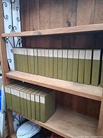 Full set of 32 green cloth bound volumes arranged on wooden shelves, spine labels visible.
