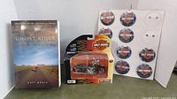 Photo showing the 'Ghost Rider' book, Maisto Harley Davidson diecast motorcycle in package, and sheet of Harley Davidson pinback buttons.