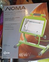 Box of NOMA portable fluorescent work light showing model details and specifications