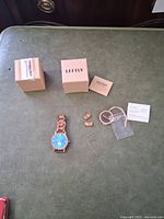 Leftly wood watch, extra links, instruction manual, tag, pins, and packaging box spread out on surface