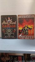 Two new metal signs, each 12" x 18", one with hot rod garage theme, the other with firefighter and motivational quote.