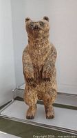 Front view of the detailed hand carved wooden bear figurine standing upright with visible facial features and fur texture.