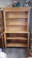 Vintage pine display cabinet in two parts: upper shelving unit and lower base with open shelf. Cabinet has natural wood finish and shows signs of wear consistent with vintage use.