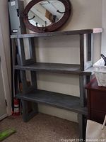 Three-tier wood and steel bench with steel legs and wooden shelves shown against wall, mirror in background not included.