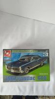Box shrinkwrapped unopened AMT brand 1967 Pontiac GTO 1/25 scale model car kit showing front and side of muscle car in dark blue.