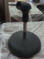 Side view of the microphone stand, showing the round base and upright rod with microphone clip.