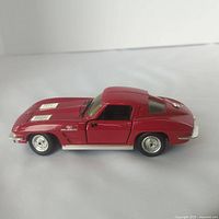 Side angle view showing red metal body, louvered hood vents, side exhaust pipes, and wire spoke wheels.