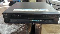 Front view of Sony 5-disc DVD/CD changer player showing main disc tray and control buttons.
