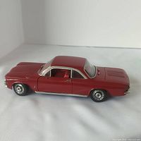 Side view of red 1/18 scale Chevy Corvair model car showing intact body and wheels.