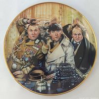 Full view of the round collector plate depicting Three Stooges in decorated military attire saluting, with gold rim and artist signature.
