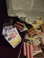 Photo showing stacks of sports cards, rolls of pennies in brown and pink wrappers, some cards in protective sleeves, and trash bags in packaging.