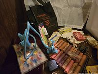 Photo showing $10 worth of pennies in pink paper rolls (marked Pennies), with assorted stationery supplies including phone holder, staples, labels, pens, clips, and a pack of cards.