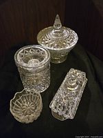 Full view of four pieces: covered bowl, lidded container, butter dish, and small bowl arranged on black cloth