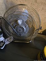 Small metal desk fan with adjustable tilt and speed control in metal cage