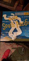 Front cover of South Pacific vinyl record with graphic design showing dancing couple and birds