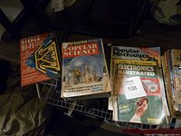 Photo showing multiple vintage magazines laid flat, including Popular Science with blueprints cover, Popular Mechanics with Electronics Illustrated insert, and Stereo Hi-Fi Guide.