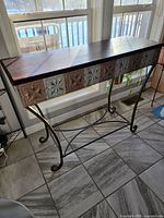 Sofa table shown from the front with clear view of patterned front and wooden top.