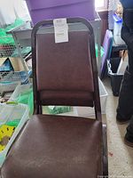 Single brown vinyl stacking chair with steel frame, showing seat and backrest upholstery and frame condition