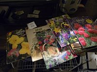 Photo showing seven vintage Ideals magazines with colorful floral covers including daffodils, tulips, irises, apple blossoms, and roses.
