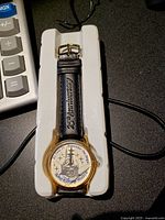 Walt Disney 25th Anniversary watch with black leather strap embossed '25th Anniversary'. Watch face shows anniversary logo with fireworks and castle.