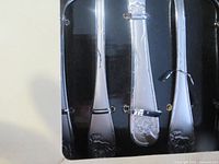 Close-up image of lodge pattern embossed flatware handles.