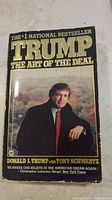 Front cover of 'Trump The Art of the Deal' paperback book with image of Donald Trump, title, author and bestseller claim.