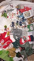 View of assorted Christmas ornaments, some boxed, tinsel, stockings, and some small holiday decorations